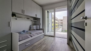 A compact bedroom with a built-in bed, storage cabinets, and a sliding glass door leading to a balcony. - Modern Retreat With a big Terrace (San Michele al Tagliamento)