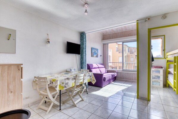 Un espacio de estar moderno con comedor, sofá, televisor y ventana.