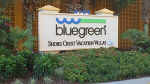 A sign for Bluegreen Shore Crest Vacation Villas with a decorative fence and tropical plants around it. - N.Myrtle Beach Oceanfront 2BR, July 20-27 Shorecrest Vacation Villas I resort (North Myrtle Beach)