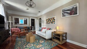 Un salon avec un canapé, une table basse, un tapis et un tableau accroché au mur.