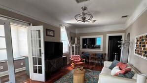 Un salon avec un canapé, un téléviseur, une table basse et un tapis à motifs.