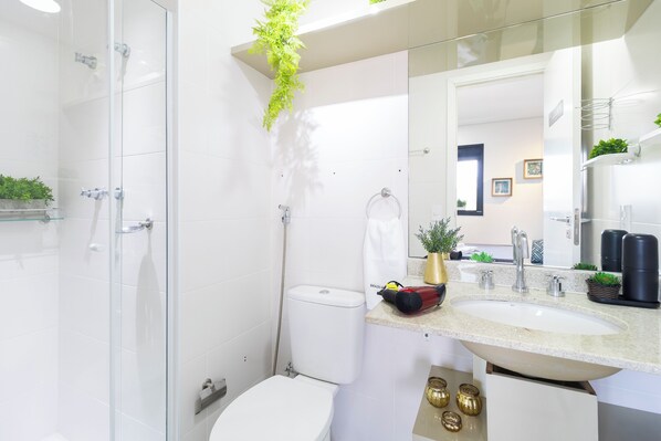 A modern bathroom with a glass shower enclosure, a white toilet, and a sink with a countertop. - Vila Mariana perto do metrô AC (Sao Paulo)