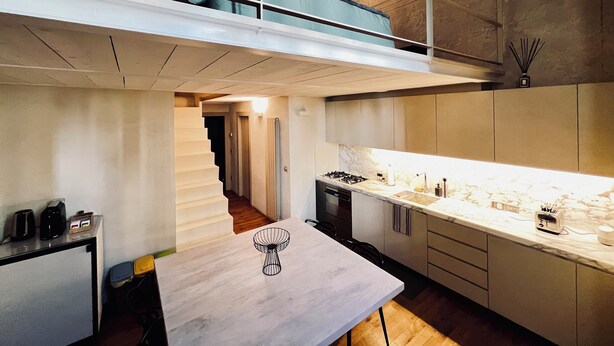 Una cocina moderna con encimera de mármol, estufa a gas y comedor con mesa y sillas.