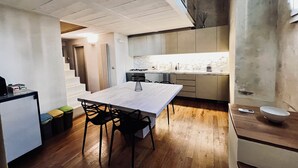 Una cocina moderna con una isla central, suelo de madera y una zona de comedor con sillas.