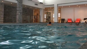 An indoor swimming pool with a wooden ceiling and stone walls.
