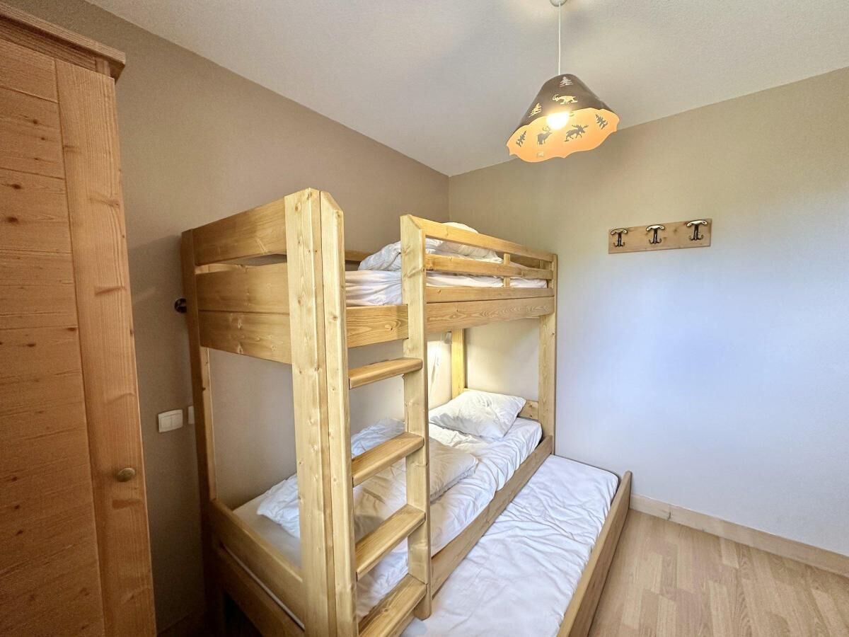 Een slaapkamer met stapelbedden, een houten garderobe, een hanglamp en een bordje aan de muur.