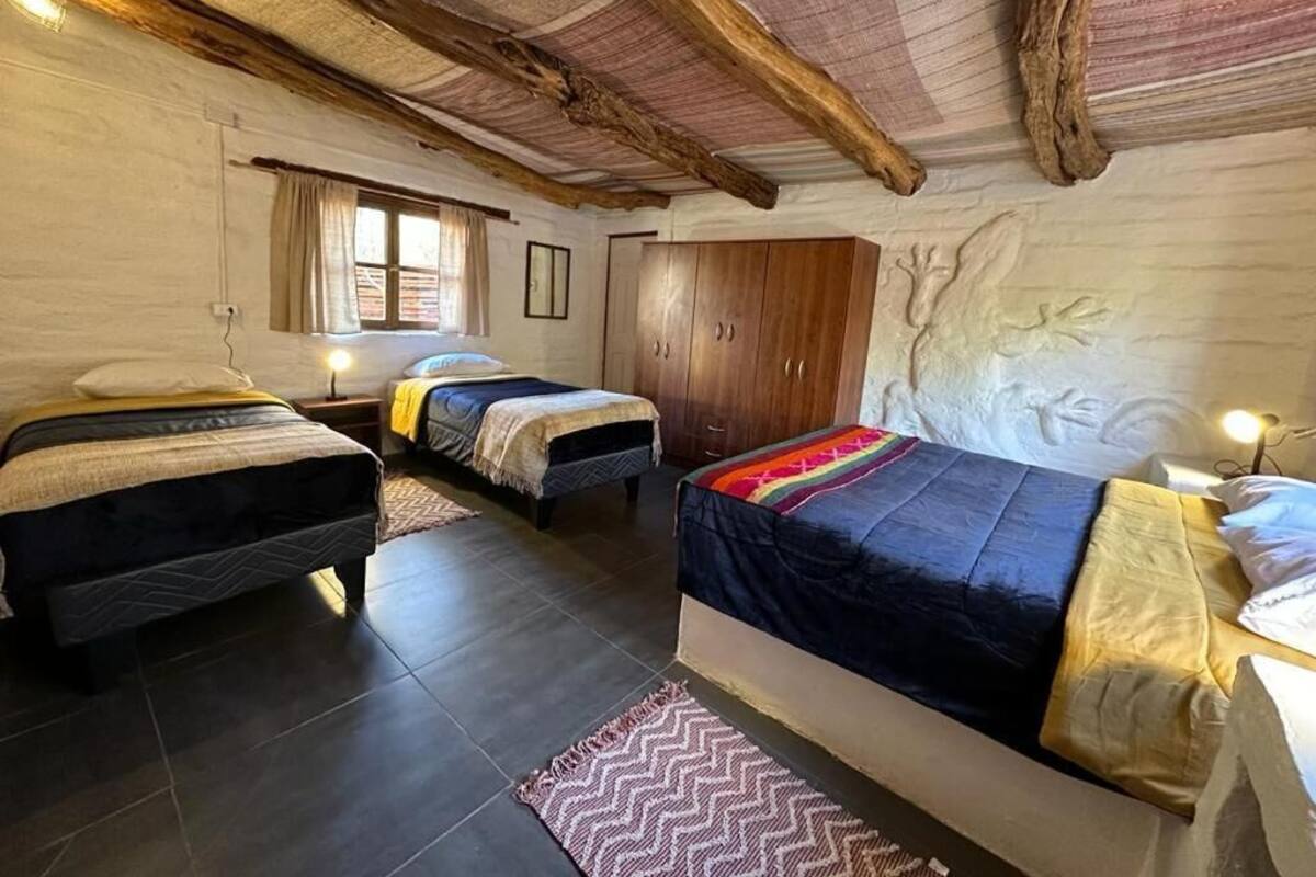 A room with two beds, a wooden ceiling, and a rustic decor.