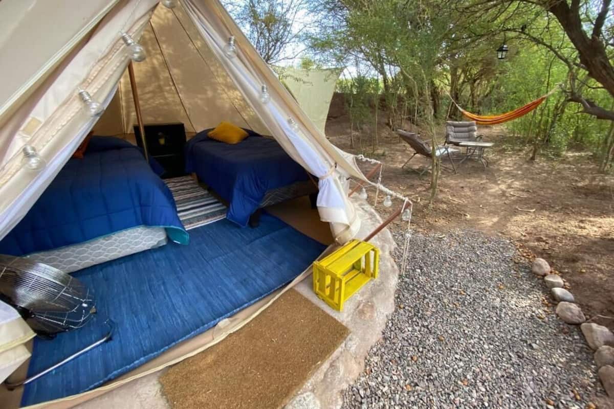 A tent with two beds, a small table, and a yellow crate.