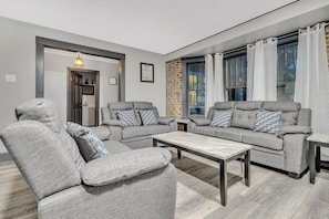 En moderne stue med grå sofaer, et træbord og en murstensvæg.