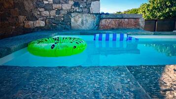 A swimming pool with a stone wall and a clear blue sky.