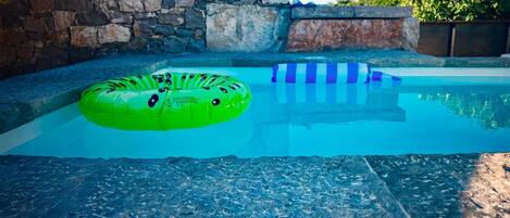 A swimming pool with a stone wall and a clear blue sky.