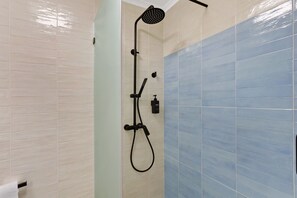 Een badkamer met een douche, betegelde wanden en een handdoekrek.
