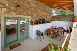 Un mur de pierre, une table en bois, une chaise, un canapé et une fenêtre avec un cadre vert.