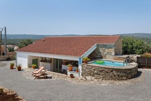 Una villa con piscina, muros de piedra y tejado de tejas rojas.