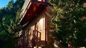 A rustic building with a wooden balcony, brick walls, and surrounding greenery. - Gueshouse di Paolo by Concavus (Campos do Jordão)