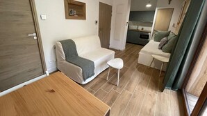 A compact living space with a sofa, a small table, and a kitchenette in the background. - 3rd floor, view mountain/forest, terrace, tv, 22m², Vars (Vars)