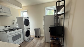 A compact kitchen with a gas stove, stacked washer and dryer, and a refrigerator.