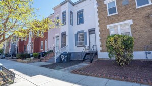 A row of townhouses with front stoops, a sidewalk, and a tree.