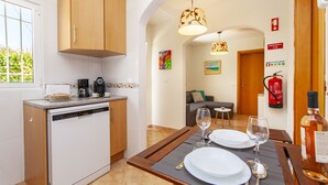 A modern kitchen with a dishwasher, a coffee maker, and a dining area set for two with plates, glasses, and cutlery. - Villa with BBQ and plunge pool in Odiáxere (Odiáxere)