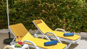 A row of yellow lounge chairs with blue towels, a fruit bowl with grapes and a watermelon slice, and a glass of orange juice. - Villa with BBQ and plunge pool in Odiáxere (Odiáxere)