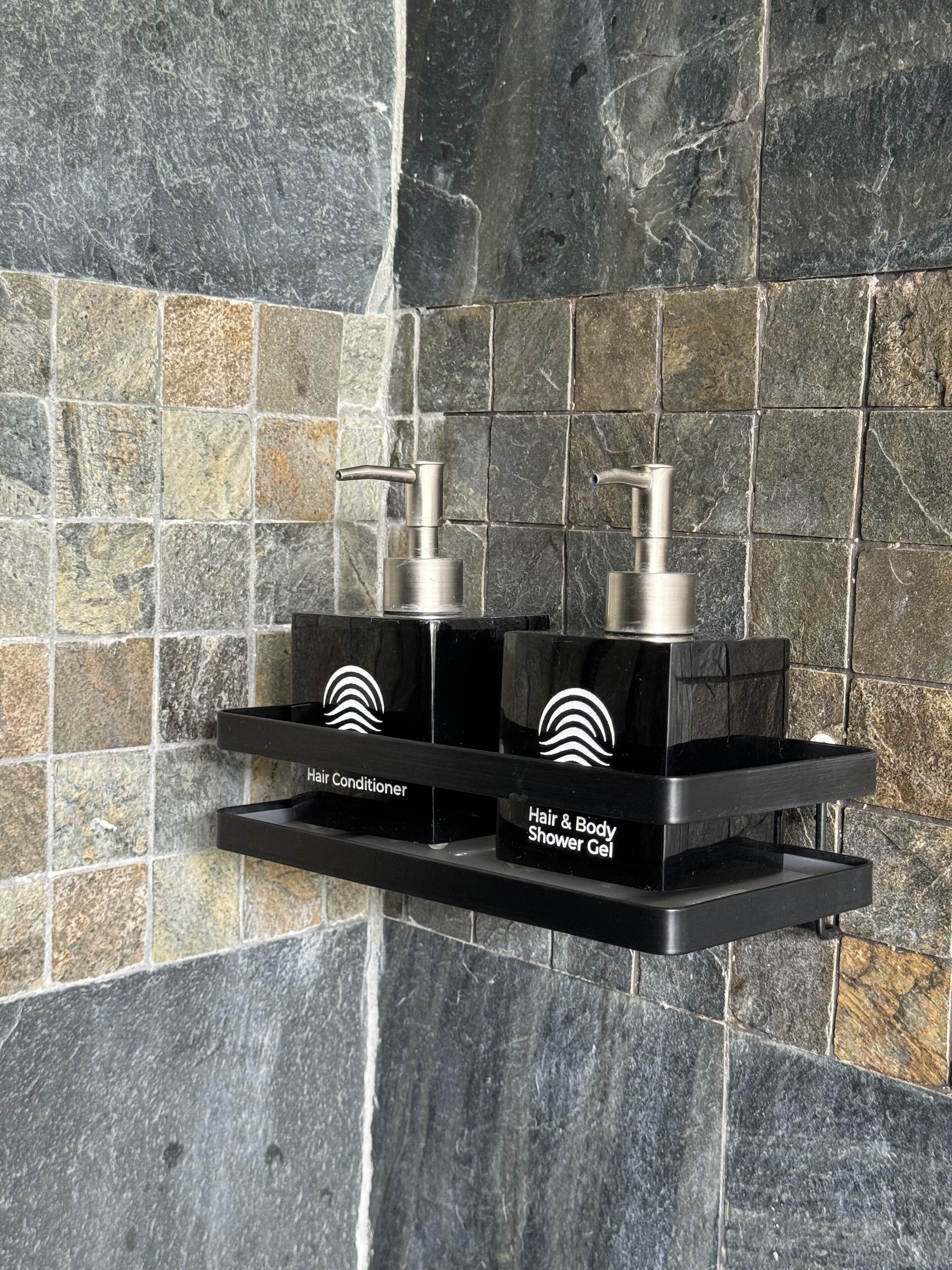 A black shelf with two pumps, one labeled "Hair Conditioner" and the other "Hair & Body Shower Gel".