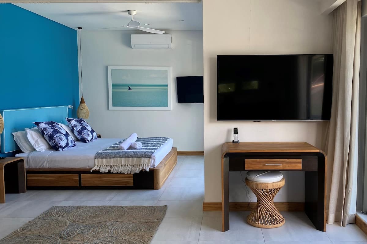 Een moderne slaapkamer met een bed, een bureau, een televisie en een groot raam.