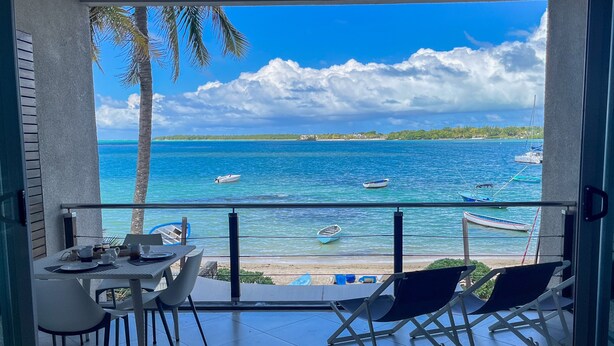 Ein Balkon mit Meerblick, einem Tisch mit Stühlen und einer Brüstung.
