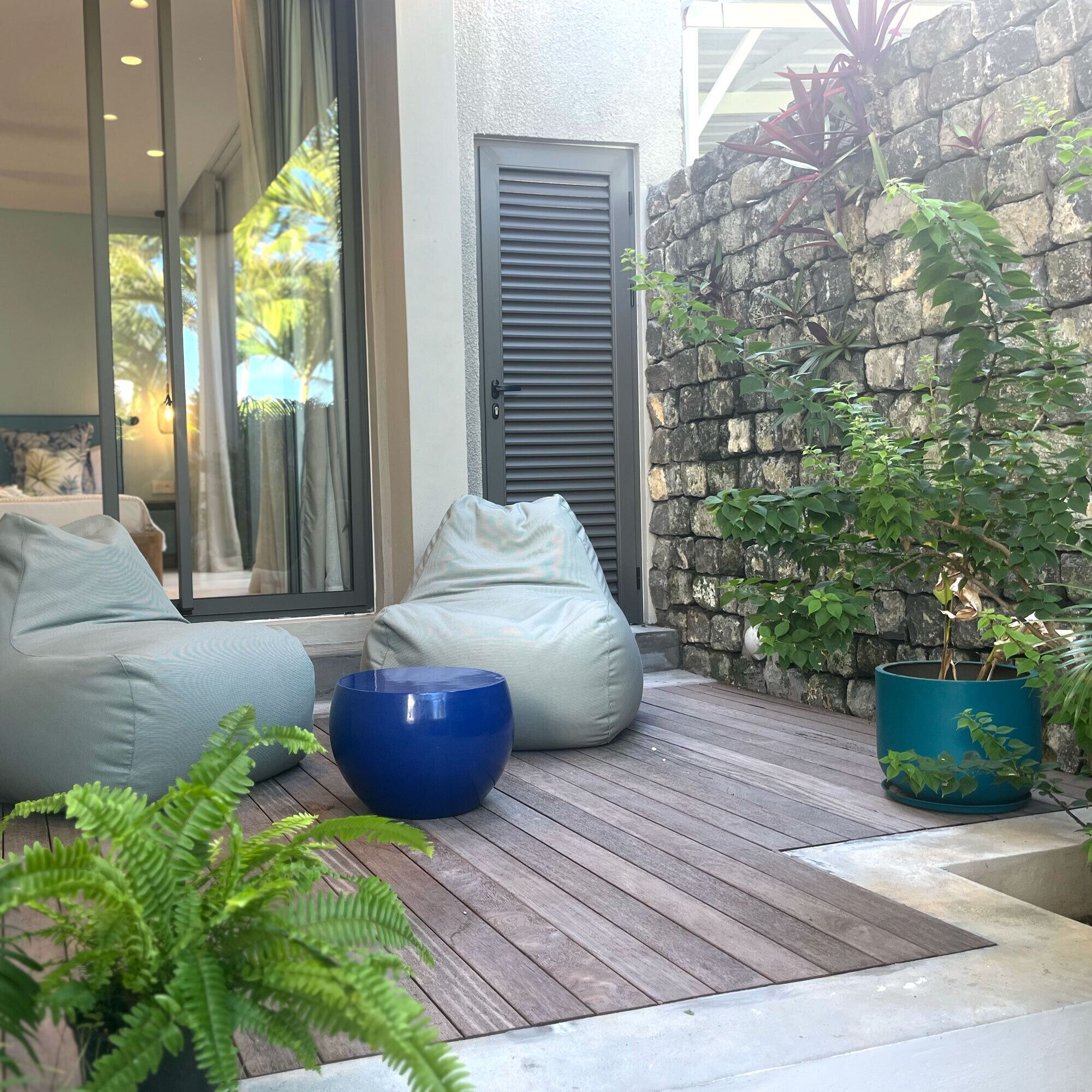 A modern outdoor seating area with a stone wall and a potted plant.