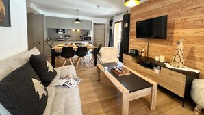 Una sala de estar moderna con sofá, mesa de centro y televisor montado en una pared de madera.