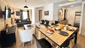 Una sala de estar moderna con piso de madera, un sofá, una mesa de comedor con sillas y una cocina con estufa.