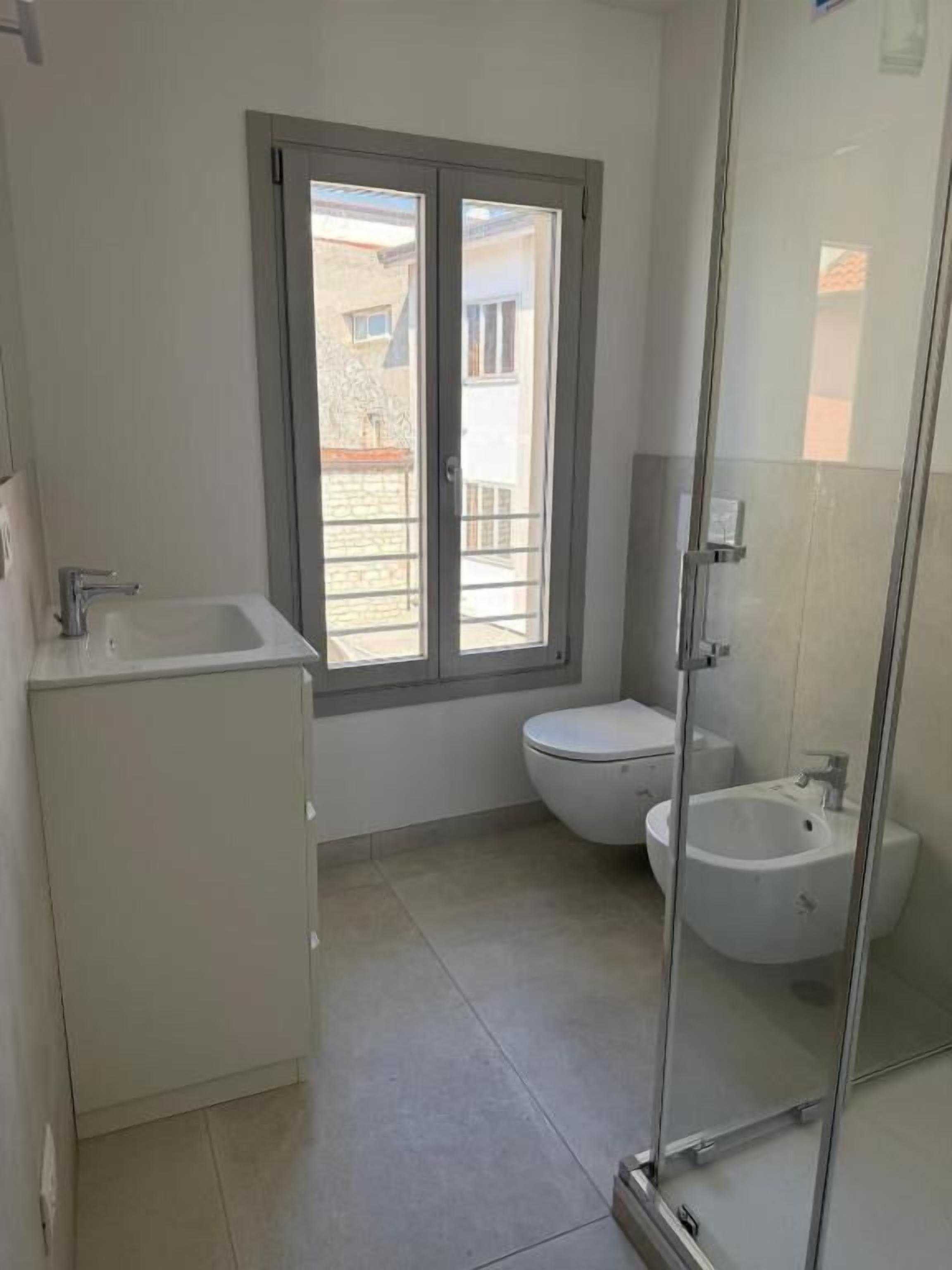 A small bathroom with a toilet, a sink, and a glass-enclosed shower.