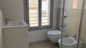 A small bathroom with a toilet, a sink, and a glass-enclosed shower.