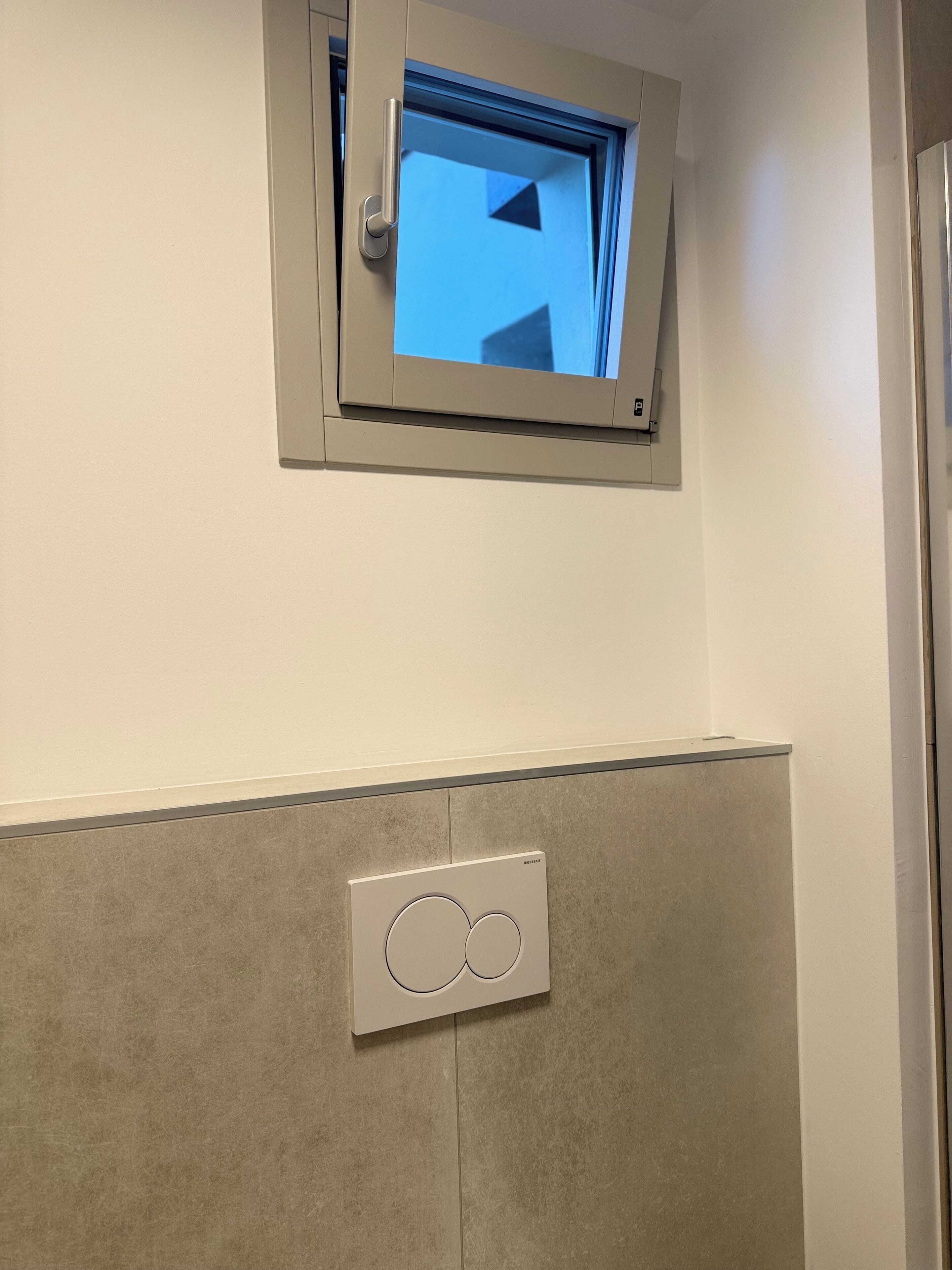 A bathroom with a window, a towel rack, and a wall-mounted light switch.