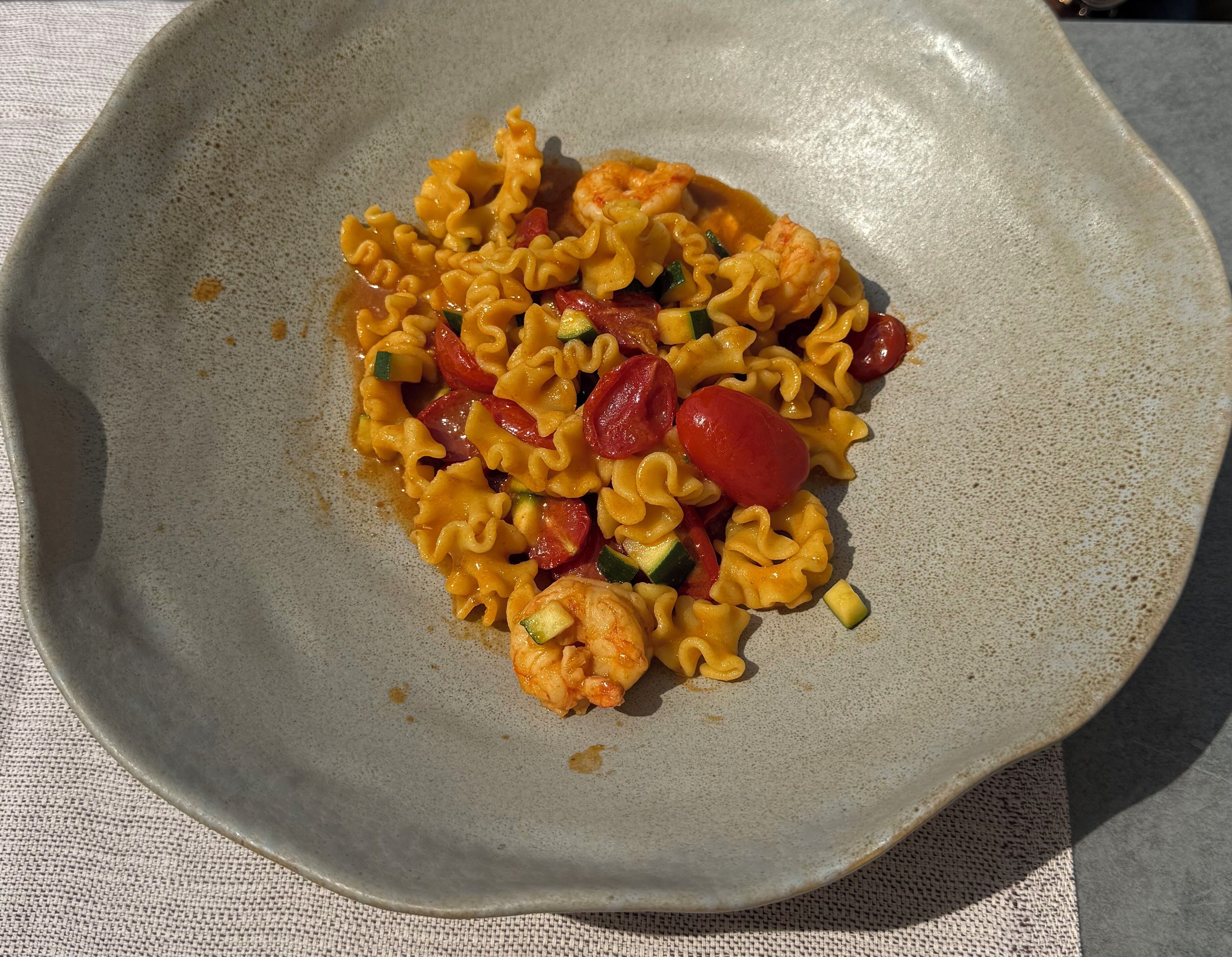 A plate of pasta with shrimp and vegetables.