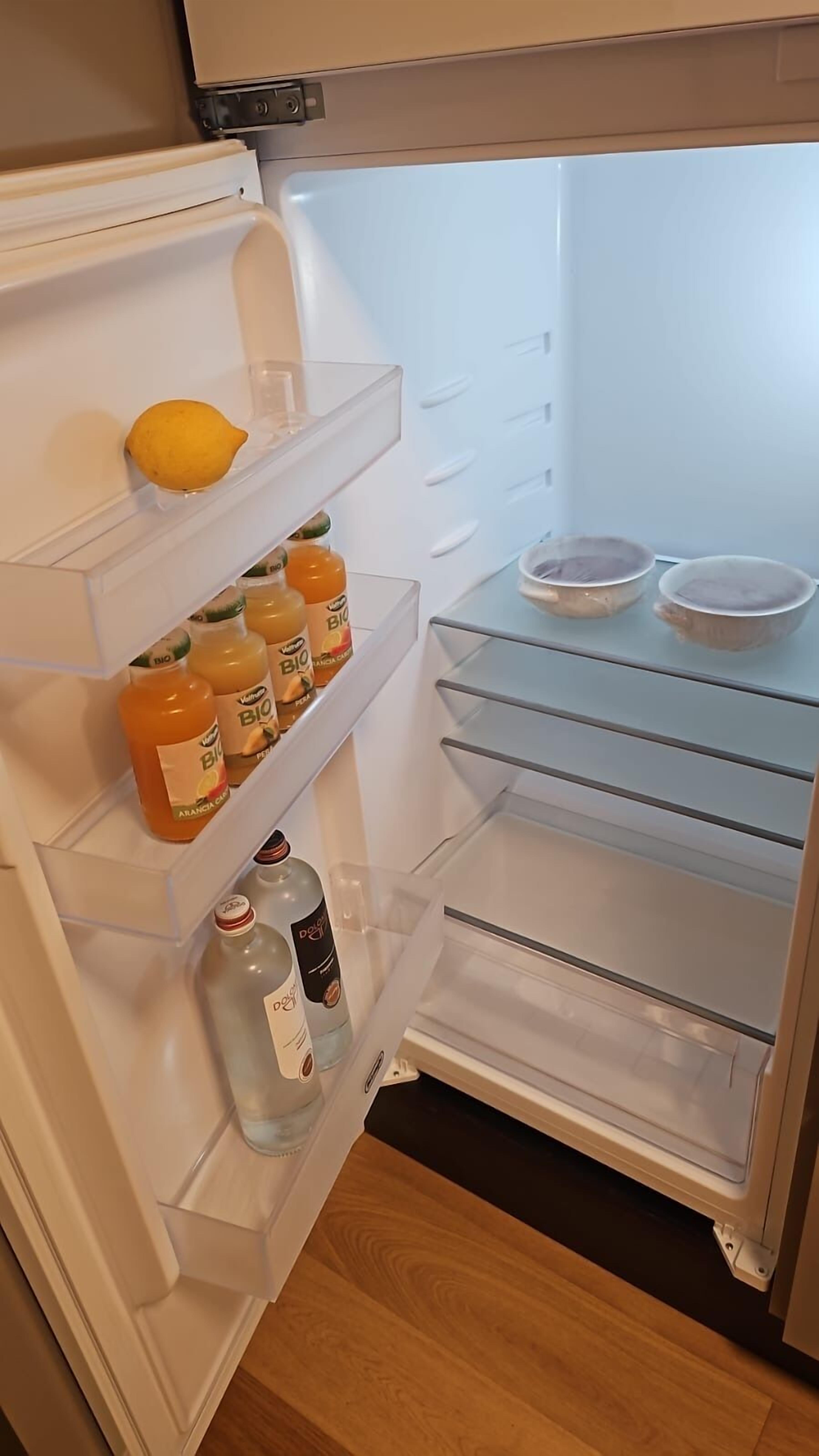 An open refrigerator with shelves containing bottles of orange juice and a bottle of water.