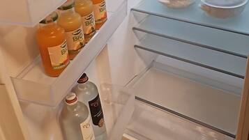 An open refrigerator with shelves containing bottles of orange juice and a bottle of water.