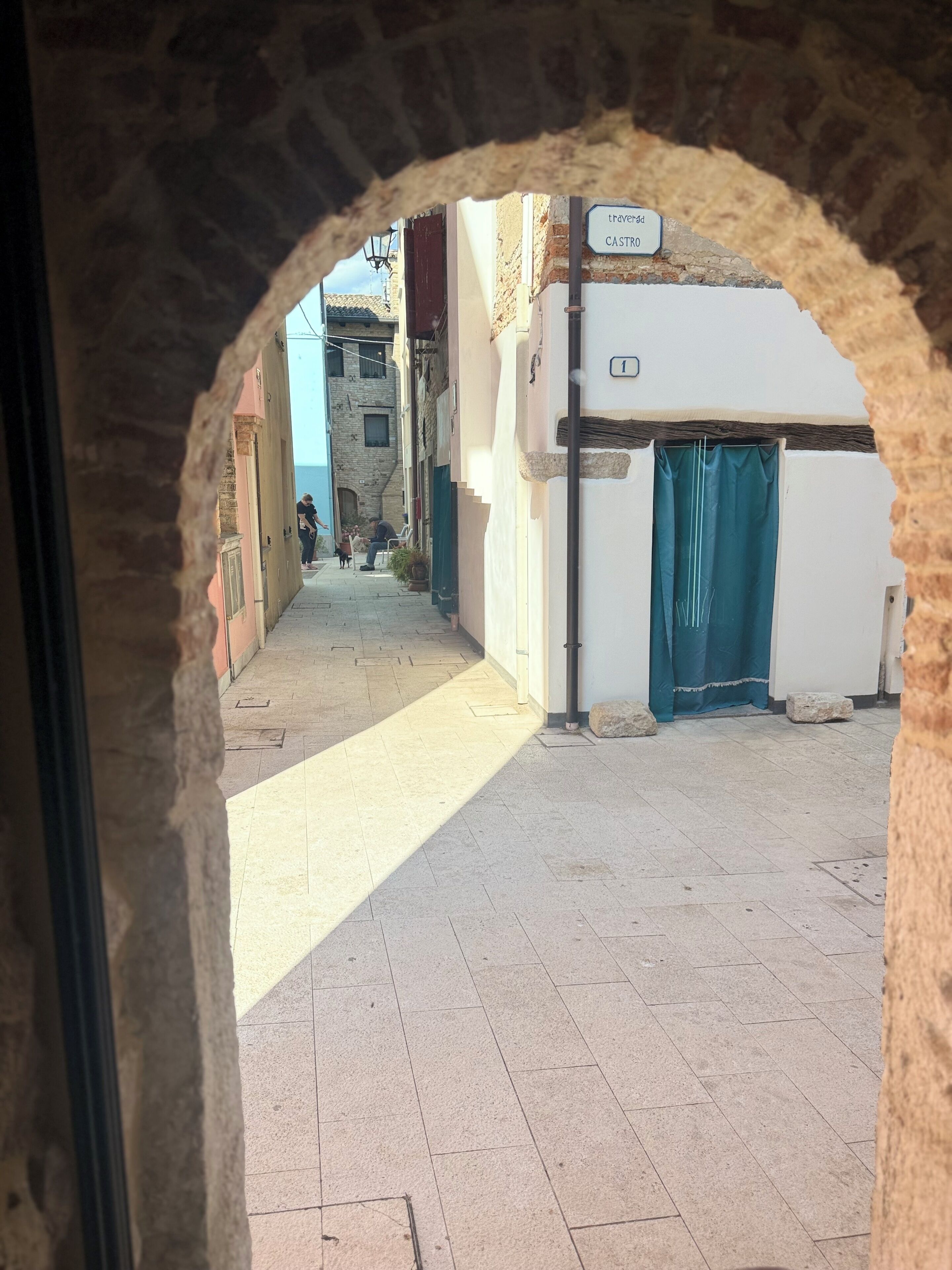 A narrow street with a stone archway leading to a building labeled "CASTRO".