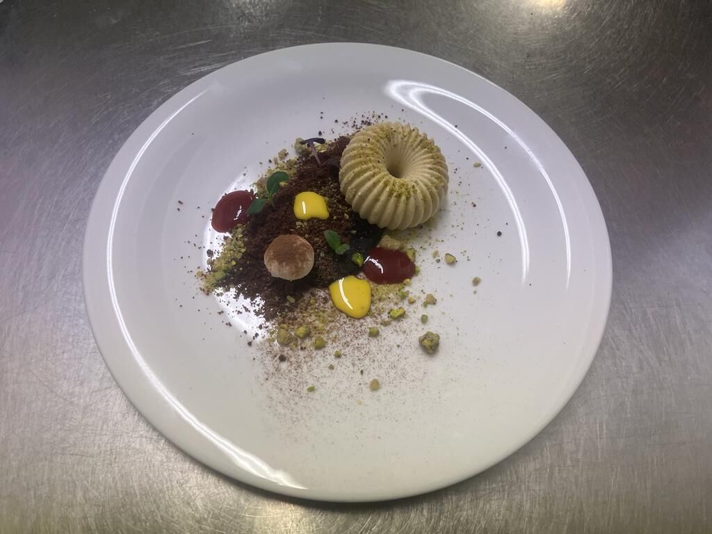 Un plato blanco con un postre sobre una superficie metálica.