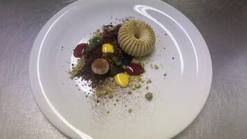 Un plato blanco con un postre sobre una superficie metálica.