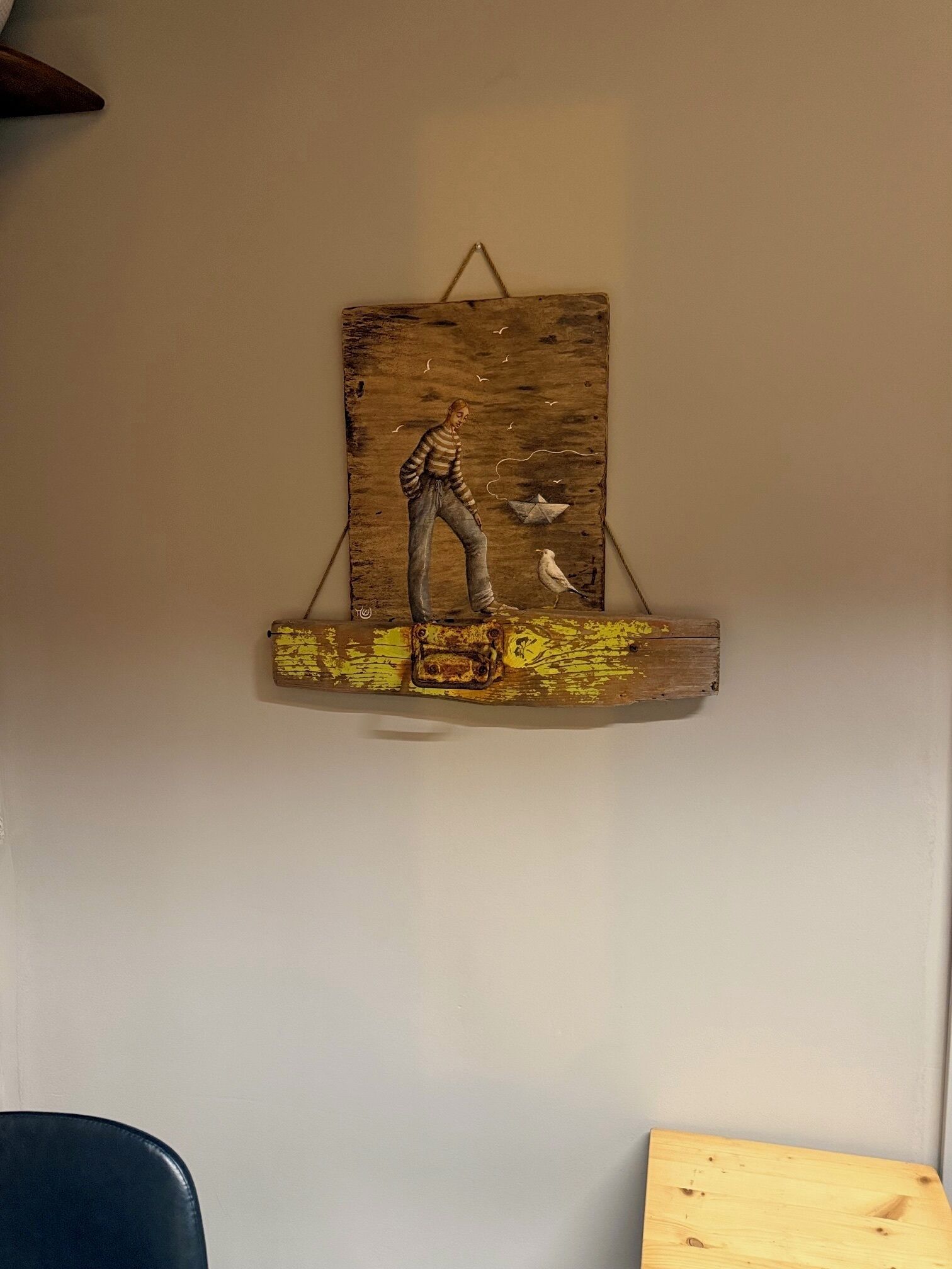 Ein rustikales Holzbild mit einer Personenfigur, die auf einer Plattform steht und einen Vogel hält.