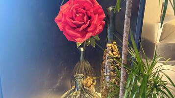 Une pièce avec un mur bleu, un vase en verre contenant une rose rouge et une petite plante.