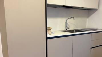 A modern kitchen with a built-in sink, a stainless steel faucet, and light grey cabinets.