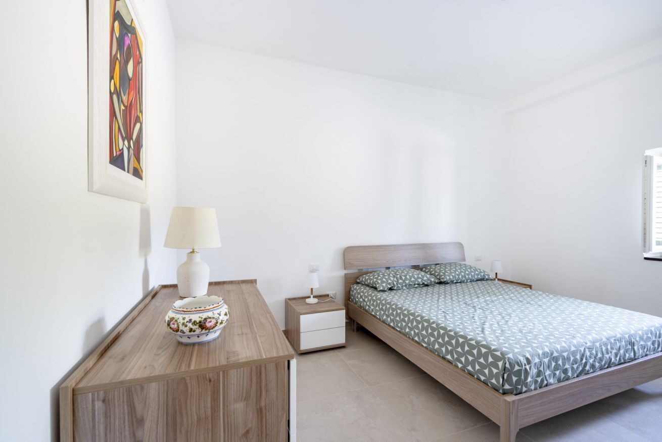 A bedroom with a bed, a bedside table, a lamp, and a framed picture on the wall.