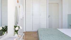 A bedroom with a bed, a wardrobe, a mirror, and a small table with a plant. - Easylife - Cosmopolitan Style in Porta Venezia (Milano)
