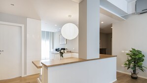 A modern kitchen with a central island, a dining area, and a visible staircase leading to another level. - Easylife - Cosmopolitan Style in Porta Venezia (Milano)