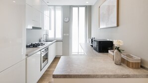 A modern kitchen with white cabinetry, a built-in oven, and a large window. - Easylife - Cosmopolitan Style in Porta Venezia (Milano)