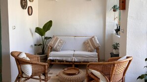 Un'accogliente zona giorno con un divano, due poltrone in vimini, un tavolino e piatti decorativi appesi alla parete.