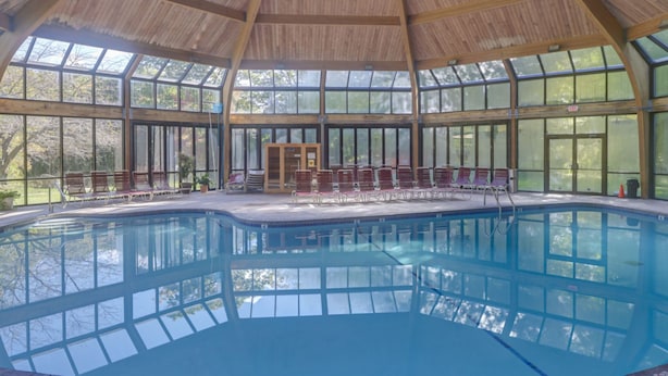 An indoor swimming pool with a wooden ceiling and large windows. - Camelback Cabin “Brand New” (Tannersville)