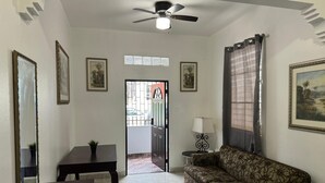 A living room with a sofa, a table, a lamp, and a ceiling fan.