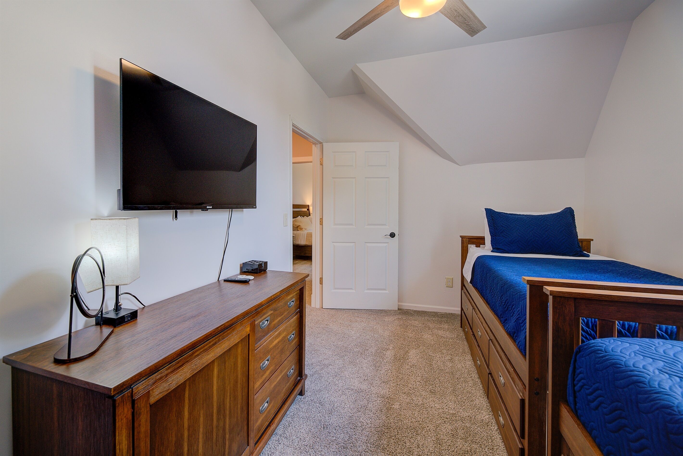 A bedroom with a bed, a dresser, a television, and a ceiling fan.